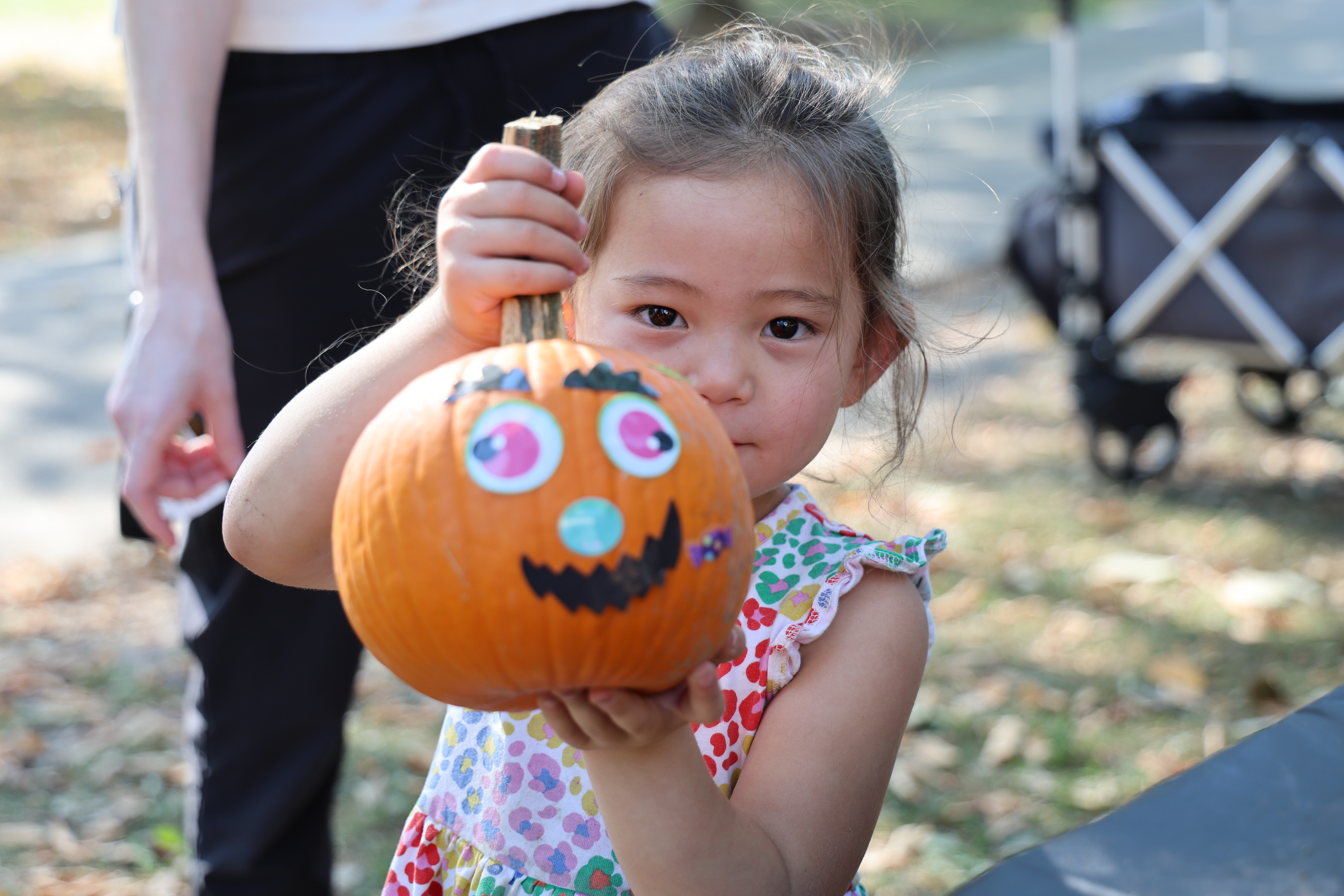 A young girl proudly holds a decorated pumpkin.